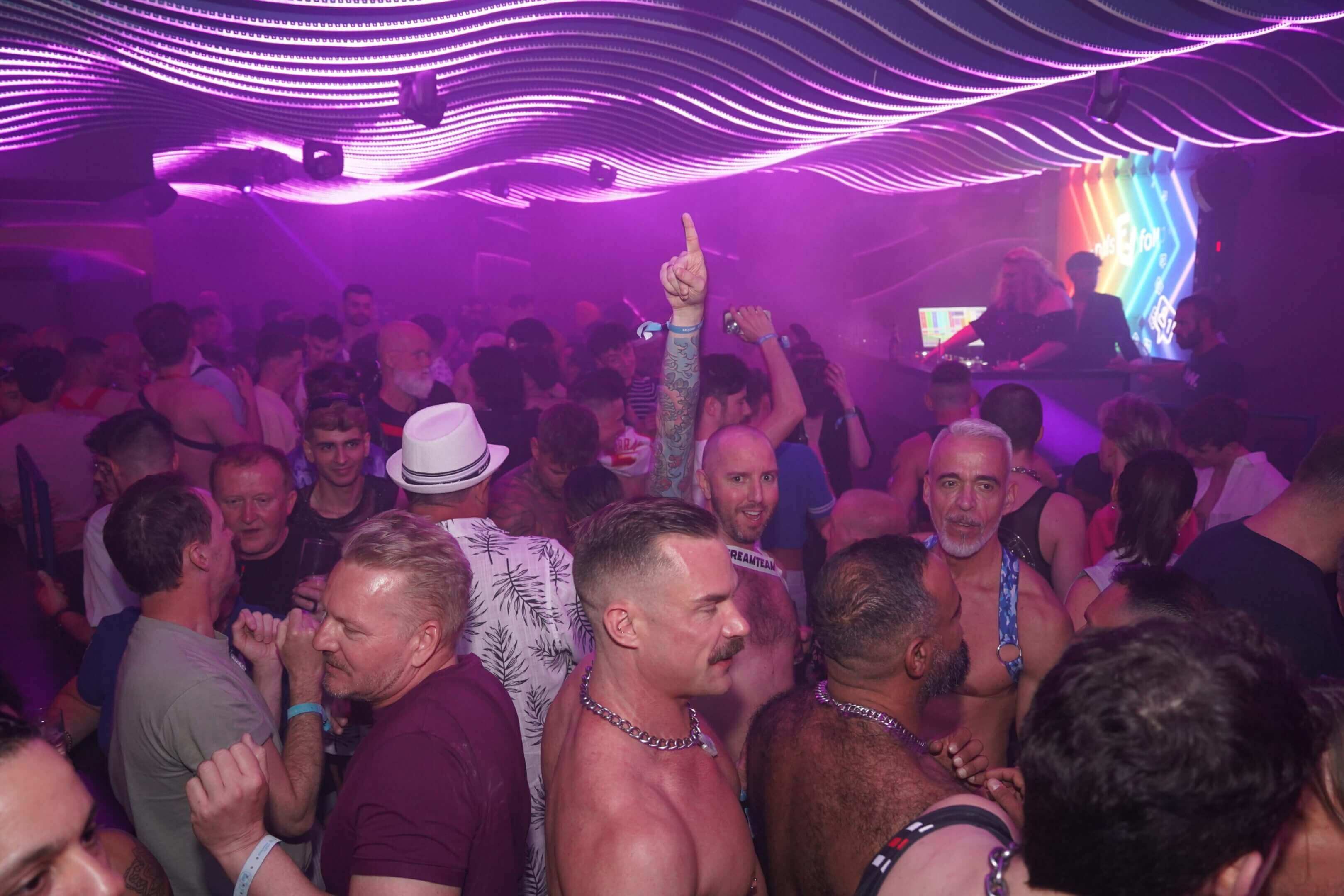 Crowded nightclub with vibrant purple lighting and energetic dancers.